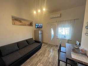 A compact living space with a sofa, a dining table, a TV, and a refrigerator.