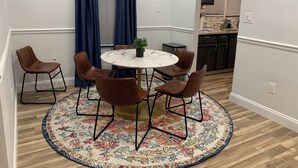 A dining area with a round table, six chairs, a potted plant, and a patterned rug. - Spacious 4-bedroom house  walking distance to Mercedes Benz Stadium & Downtown (Atlanta)