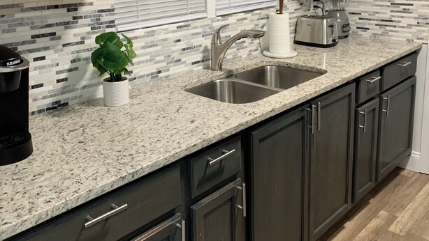 A modern kitchen with dark cabinets, a granite countertop, a sink, a toaster, and a coffee maker. - Spacious 4-bedroom house  walking distance to Mercedes Benz Stadium & Downtown (Atlanta)