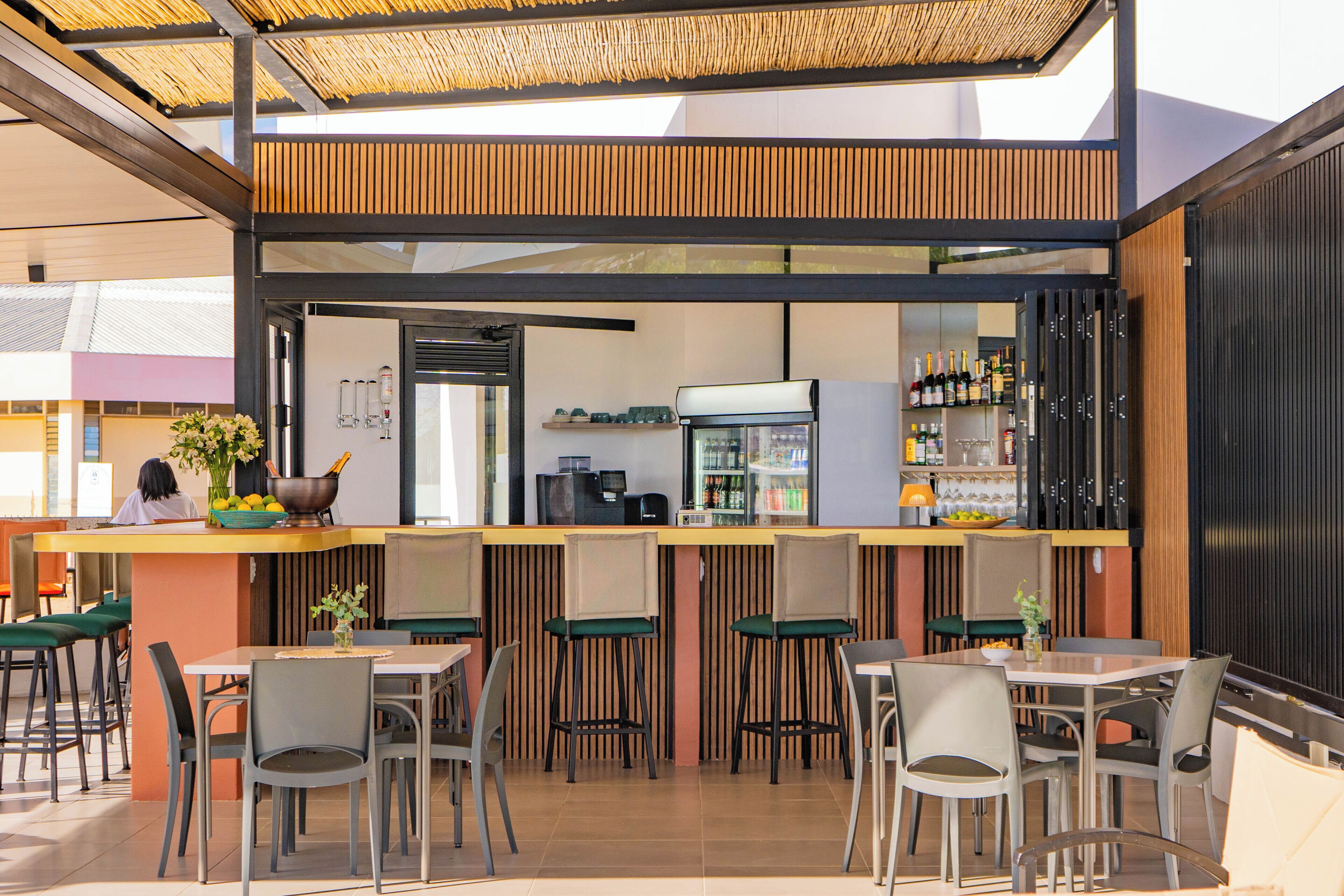 An outdoor cafe with a counter, seating, and a refrigerator.
