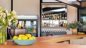 A bar area with a bowl of lemons and a vase of flowers on the counter, a wine rack with bottles, and a potted plant. - TaTe Village - Hostel (Windhoek)