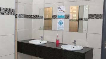 A bathroom with two sinks, a mirror, and a hand sanitizer dispenser.