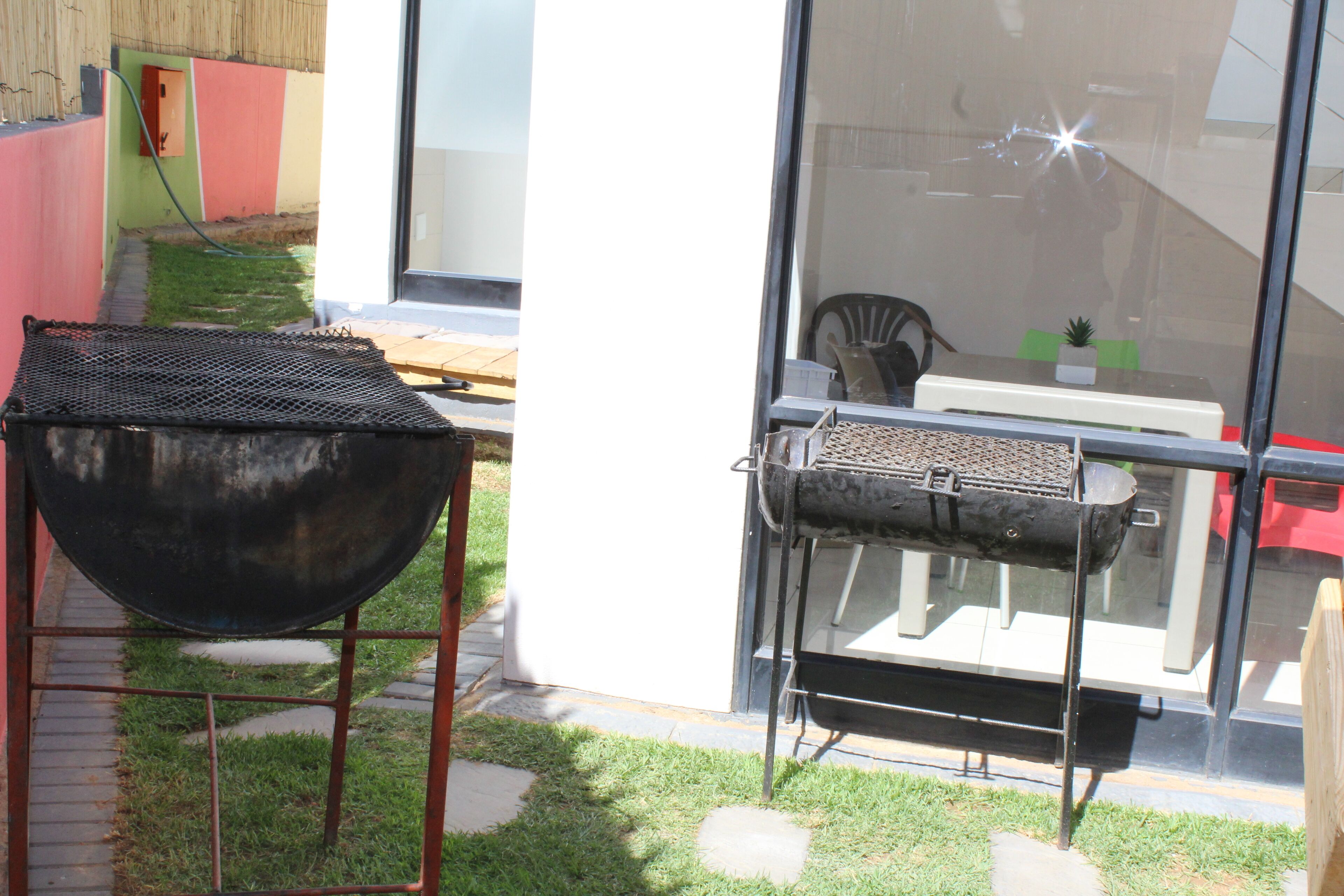 A backyard with a grill, a table, and a chair.