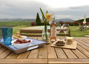 A wooden table set with a tray of strawberries, a bottle of wine, glasses, and a vase with flowers. - Villa with private pool and panoramic view in beautiful Val d'Orcia (San Giovanni d'Asso)