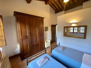 A bedroom with two beds, wooden wardrobe, and a mirror on the wall. - Villa with private pool and panoramic view in beautiful Val d'Orcia (San Giovanni d'Asso)
