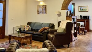 A cozy living room with a wooden ceiling, a sofa, a chair, and a coffee table. - Villa with private pool and panoramic view in beautiful Val d'Orcia (San Giovanni d'Asso)