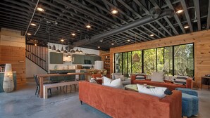 Ein großzügiger Wohnbereich mit einem großen orangefarbenen Sofa, einem Esstisch mit Stühlen und einer Küchenzeile mit grünen Schränken sowie einem großen Fenster.