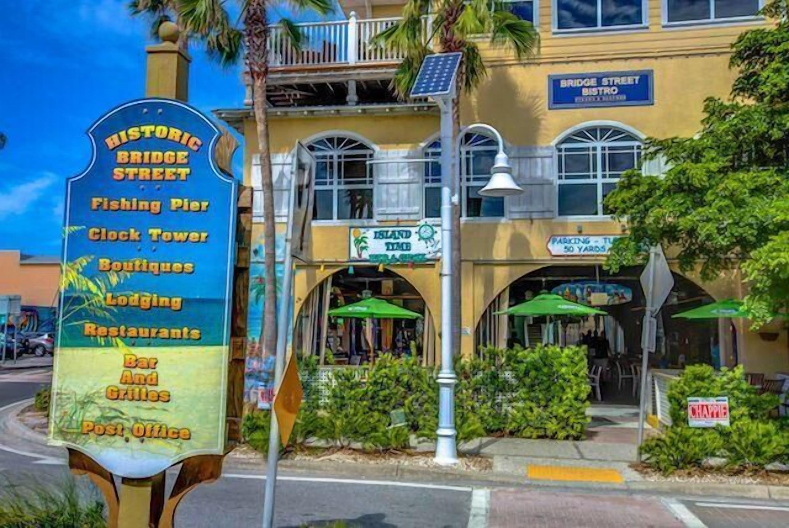 Un cartel histórico que enumera servicios como un muelle de pesca, una torre del reloj, boutiques, alojamientos, restaurantes, bares, parrillas y una oficina de correos.