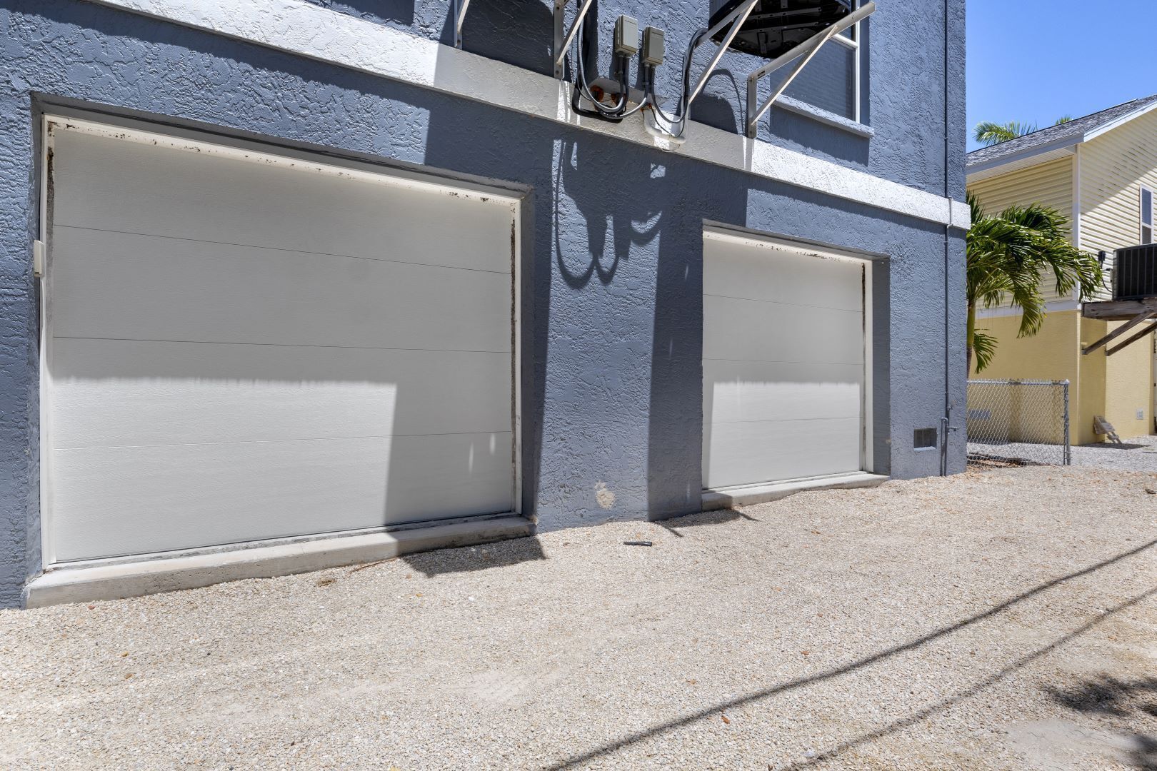 A two-story building with two garage doors and a security camera mounted on the wall.