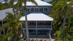 A two-story house with a balcony, surrounded by palm trees. - Getaway By The Bay-4 bedrooms-Large private pool and spa across from the bay!! (Bradenton Beach)
