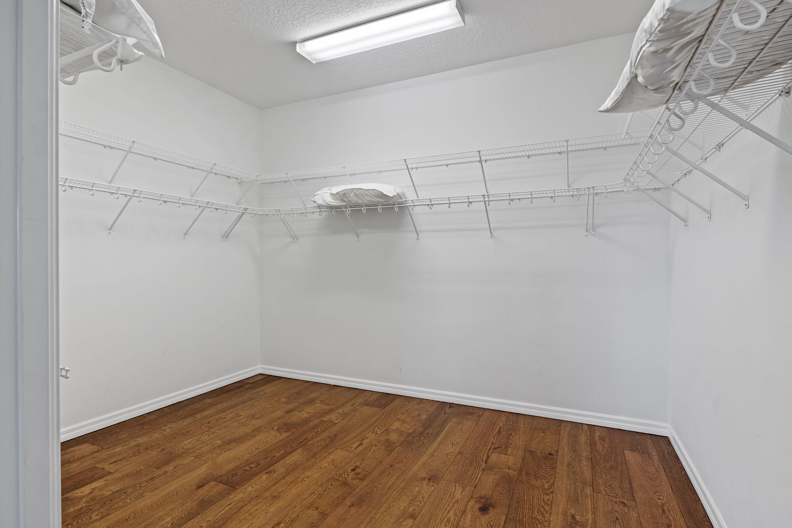 A room with a wooden floor, white walls, and a ceiling fan.