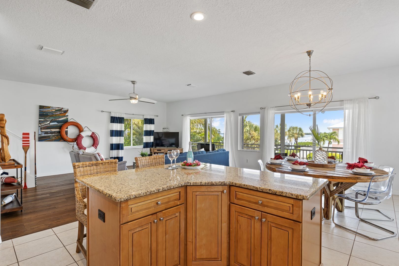 Cocina moderna con una isla grande, armarios de madera y comedor con vistas al exterior.