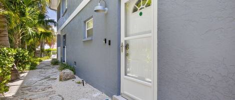 A building with a white door, a small window, and a wall-mounted light fixture.