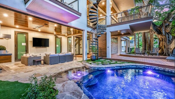 A modern house with a swimming pool, outdoor seating, and a spiral staircase.
