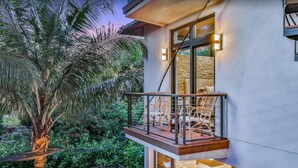 A modern building with a balcony, outdoor seating, and a stone wall.