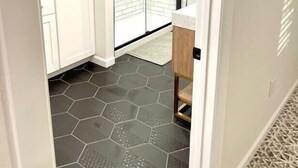 A narrow hallway with a white door, a white cabinet, and a black-framed sliding door leading to a balcony. - Boho 405 - DI Home Rentals (Stillwater)