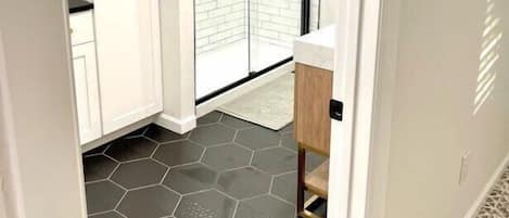 A narrow hallway with a white door, a white cabinet, and a black-framed sliding door leading to a balcony.