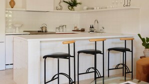 A modern kitchen with a central island, bar stools, and pendant lighting.