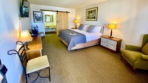 Une chambre d’hôtel comprenant un lit, des tables de chevet, un bureau, une chaise, une armoire et une salle de bain.