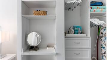 Een witte badkamer met een wastafel, een ronde spiegel, een plank met toiletartikelen en een handdoekhouder.