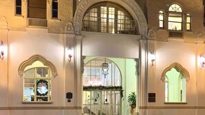 Un edificio grande e histórico con una entrada imponente, múltiples ventanas y un arco central.
