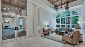 Amplia sala de estar con chimenea, asientos cómodos y grandes ventanales con vistas al exterior.