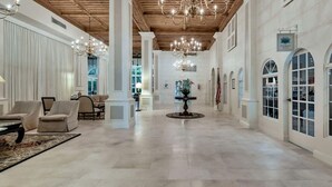 Un vestíbulo amplio con techos altos, candelabros y una mesa central.