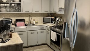 Eine moderne Küche mit grauen Schränken, einem Edelstahl-Kühlschrank, einer Mikrowelle und einem Gasherd.