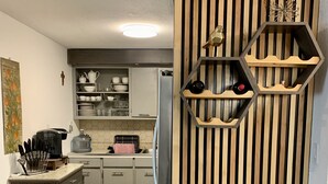 Eine moderne Küche mit einer Wand in Holzoptik, einem eingebauten Kühlschrank und einer Kaffeemaschine.