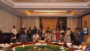 Evento formal con un grupo de personas vestidas con atuendos tradicionales alrededor de una mesa decorada.
