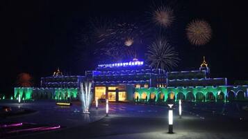 A building with illuminated arches and a fountain in the foreground.