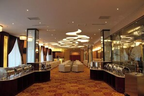 Un vestíbulo de hotel con una larga recepción, una alfombra estampada y luminarias modernas.