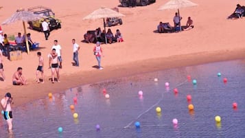 A beach with people, a water body, and a dune buggy.
