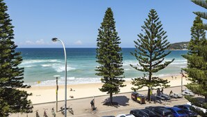Una spiaggia con vista sull'oceano, un'area parcheggio con auto e alcune persone che passeggiano.