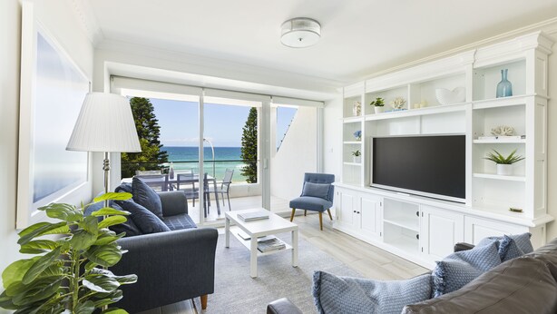 Un soggiorno moderno con una grande TV, posti a sedere confortevoli e vista sull'oceano.