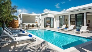 Un espace piscine moderne avec des chaises longues et un bar.