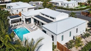 Un immeuble résidentiel moderne doté d’une piscine, de panneaux solaires et d’une cour clôturée.