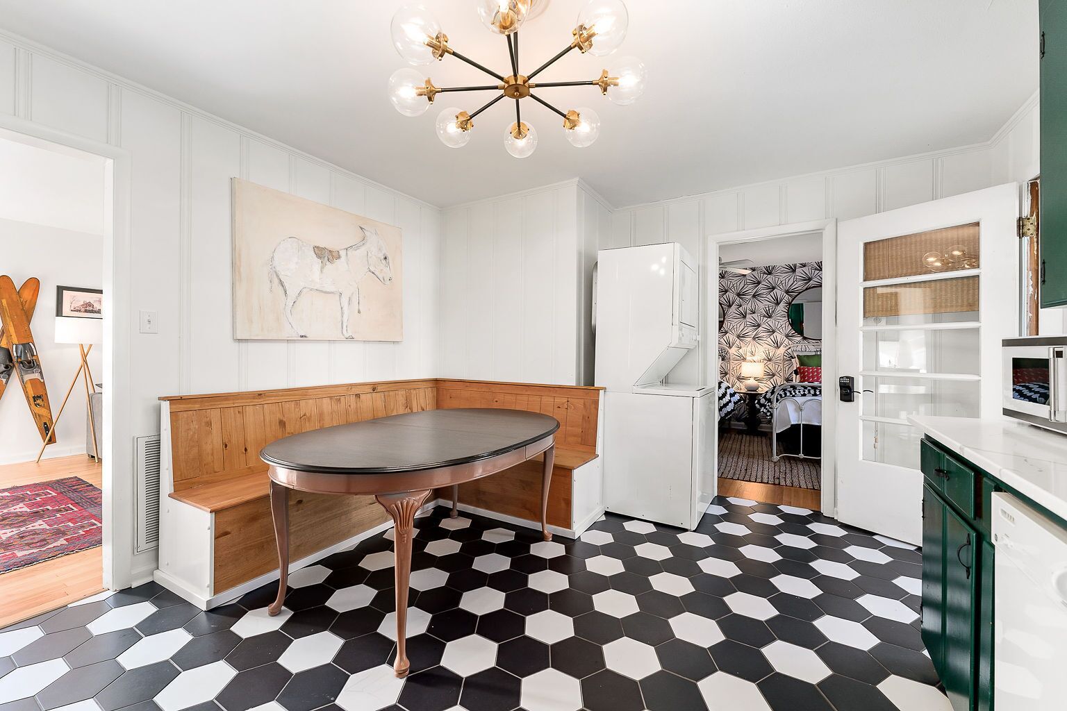 Une cuisine moderne avec une table ronde, des meubles blancs et un sol carrelé de motifs hexagonaux noirs et blancs.