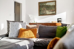 A modern living room with a sofa, a painting, and a wooden dresser.