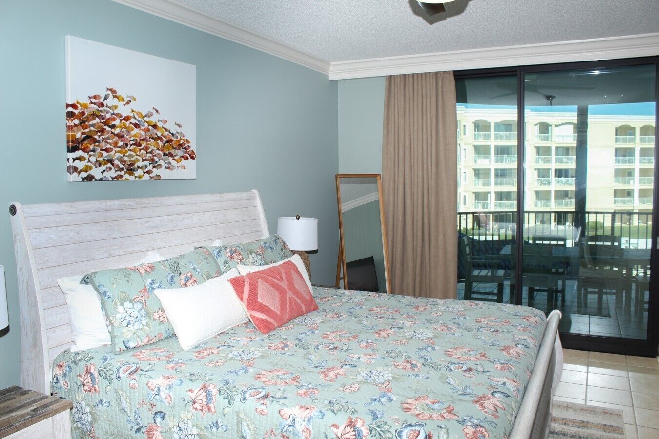 Una camera d'albergo con un letto, un quadro, vista su un edificio e un balcone.