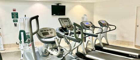 Une salle de sport équipée de tapis de course et d'appareils d'exercice.