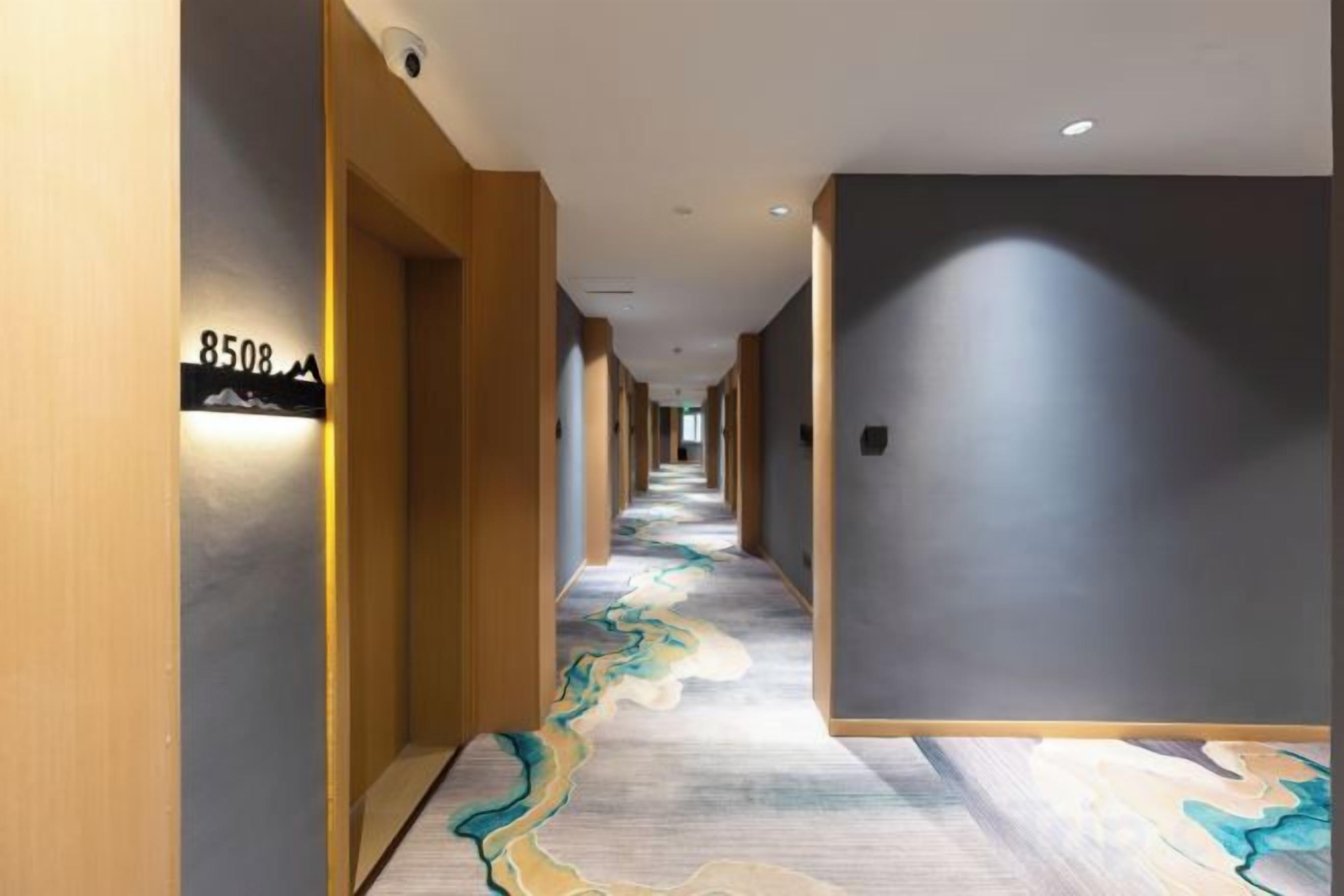 A hotel corridor with a carpeted floor, wooden walls, and a sign indicating room number 8508.