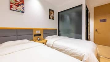 A hotel room with two beds, a bedside table with a phone, and a door with a sign.