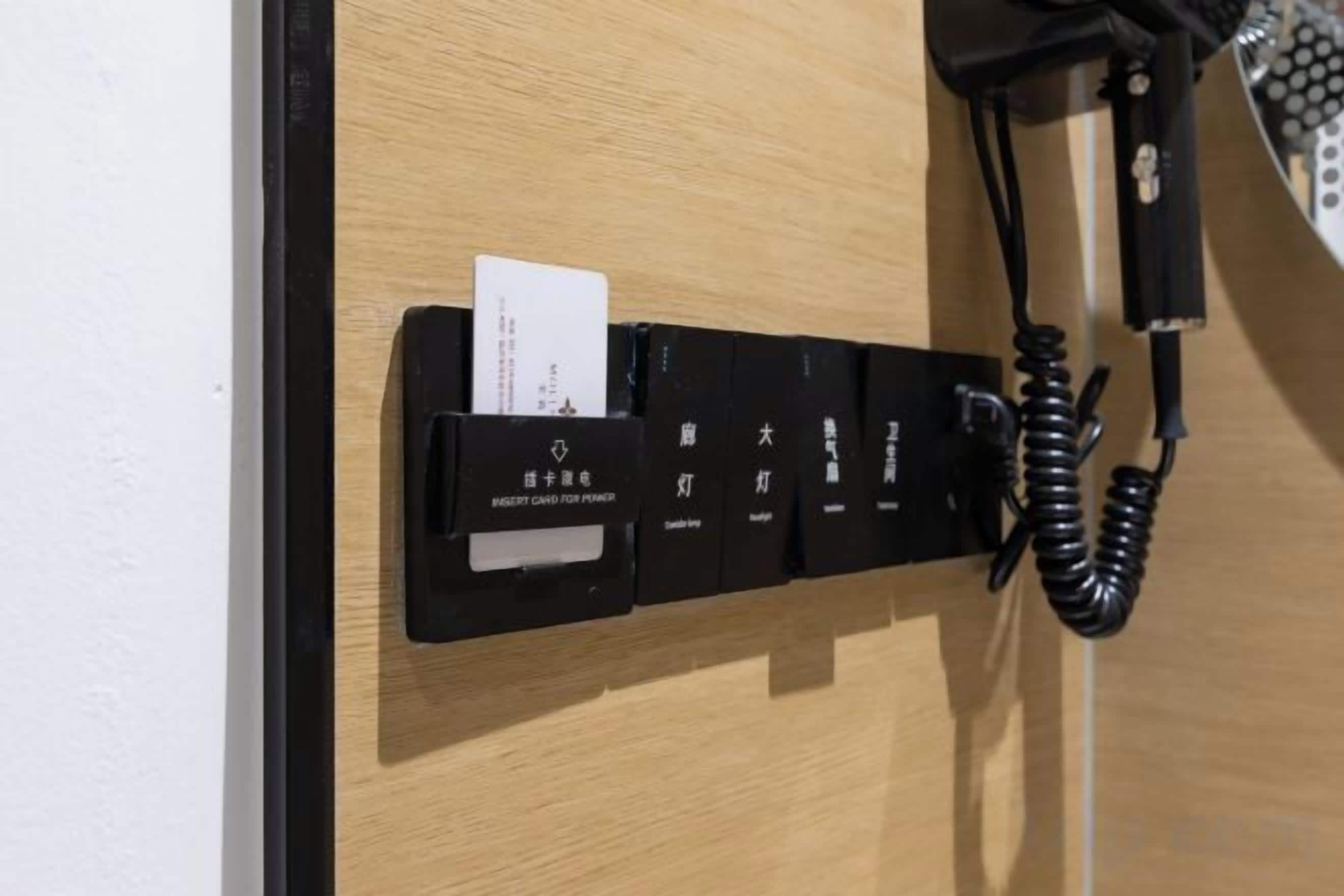 Puerta de una habitación de hotel con un teléfono negro y un lector de tarjetas.