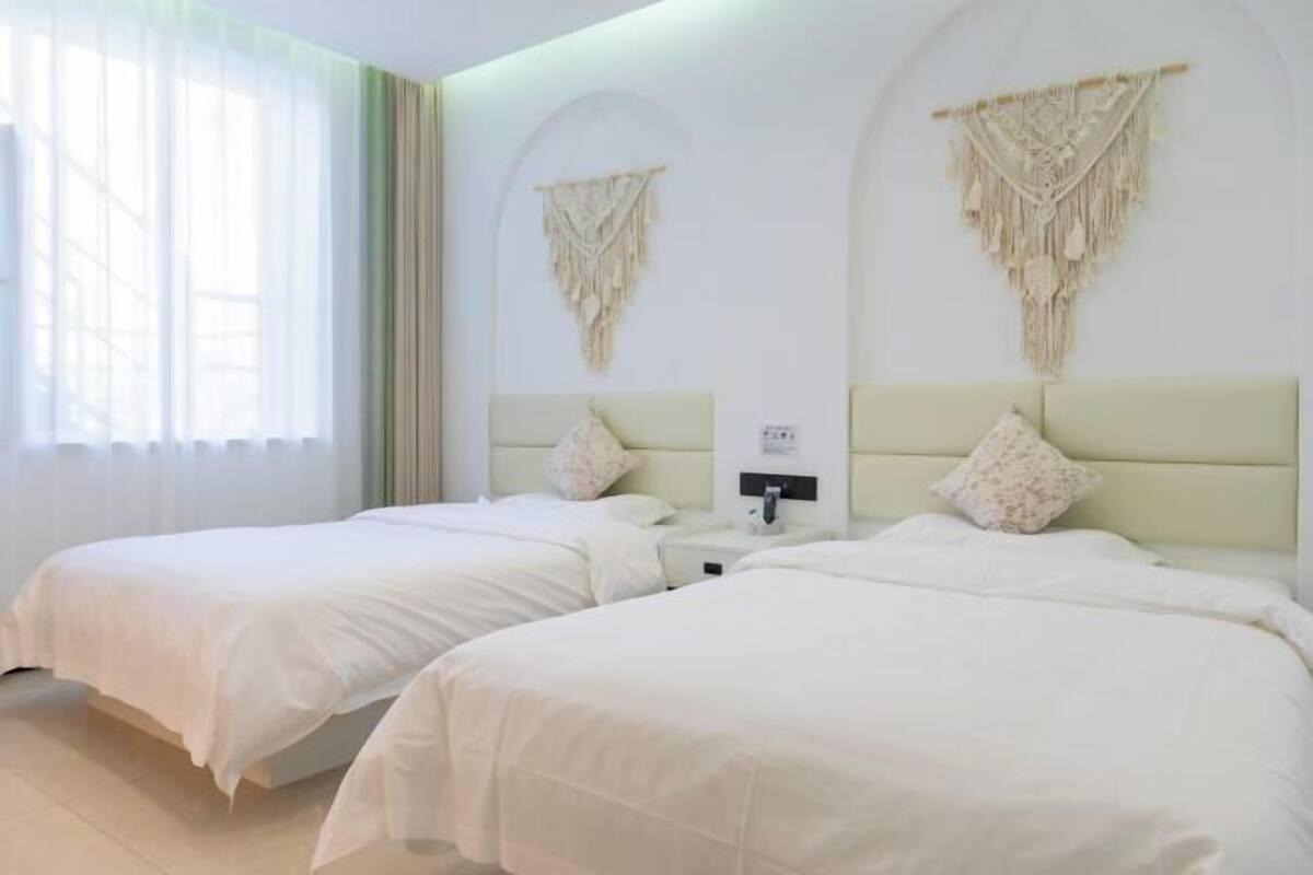 Une chambre d’hôtel avec deux lits, une table de chevet et une lampe fixée au mur.