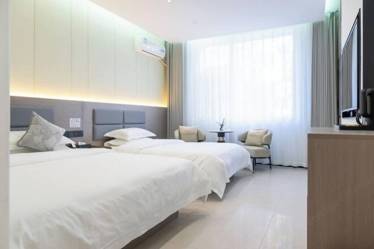 Une chambre d’hôtel avec deux lits, une petite table, une chaise et un téléviseur.
