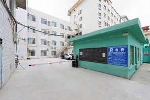 A gated parking area with a blue sign, a white building in the background, and a clear sky.