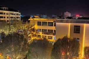Un edificio de varios pisos con balcones y una superficie acuática reflectante al frente.