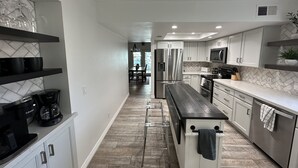 Una cocina moderna con armarios blancos, electrodomésticos de acero inoxidable y un revestimiento de baldosas en patrón de espiga.