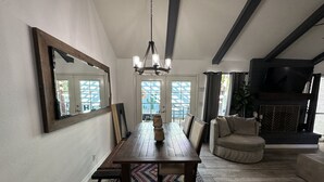Un comedor con una mesa de madera, sillas, una lámpara de araña y una alfombra estampada.
